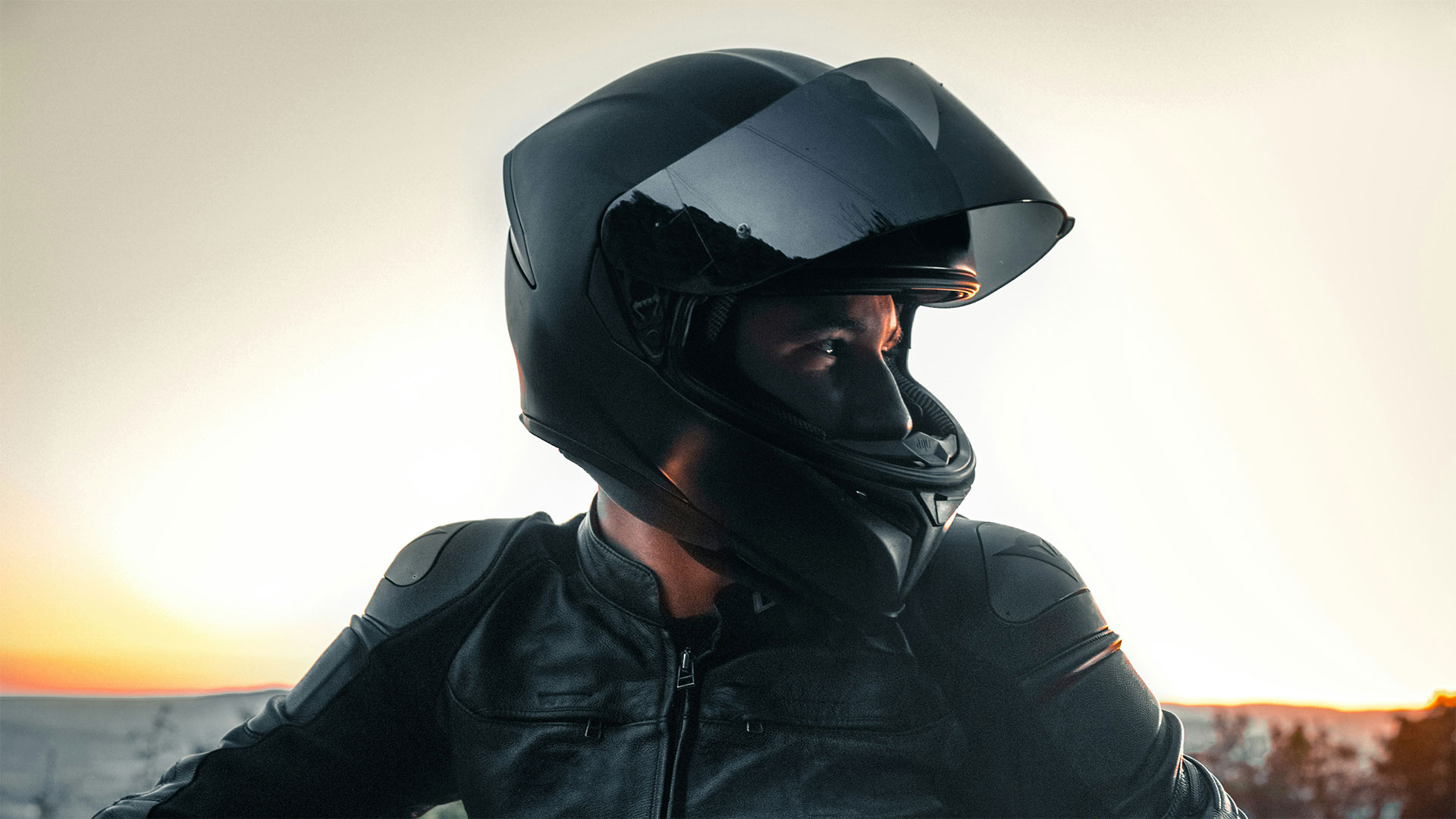 Ein Motorradfahrer in einer schwarzen Lederkombi blickt aus seinem Helm